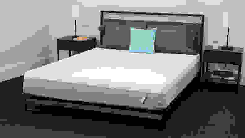 A mattress in a bedroom with bedside tables on either side.