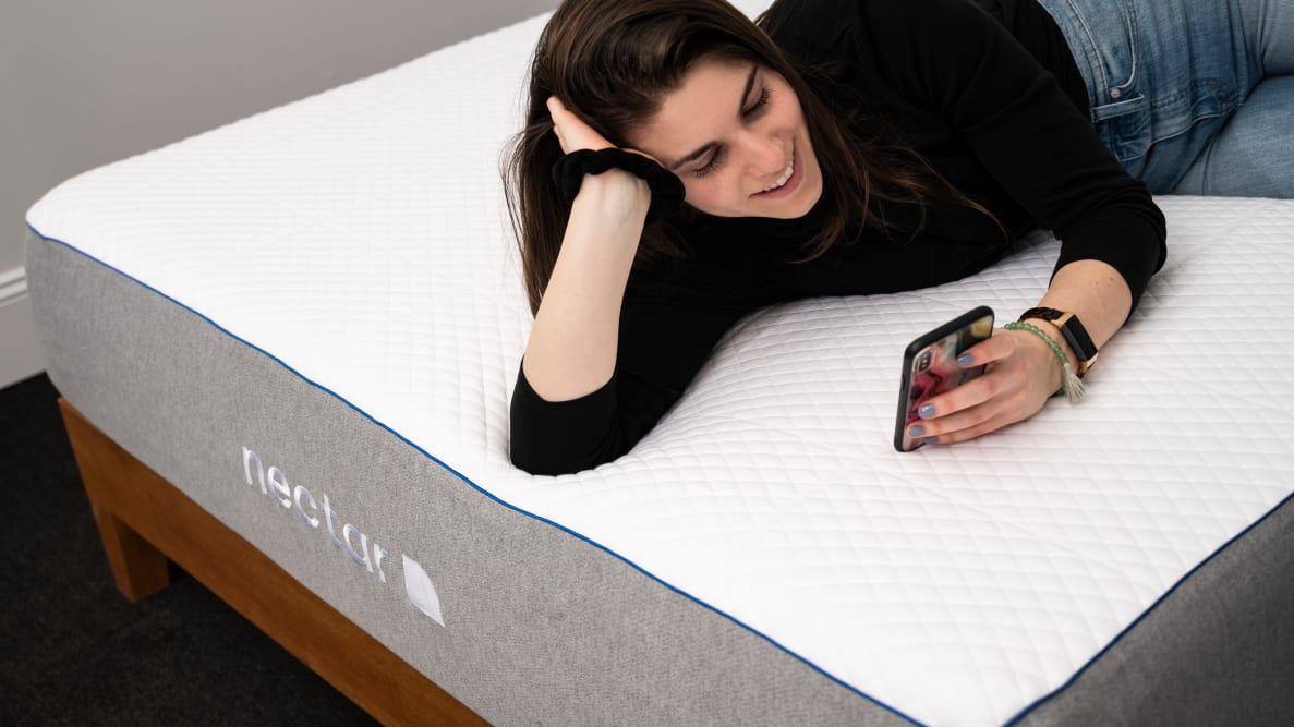 一个女人躺在花蜜床垫上看手机
