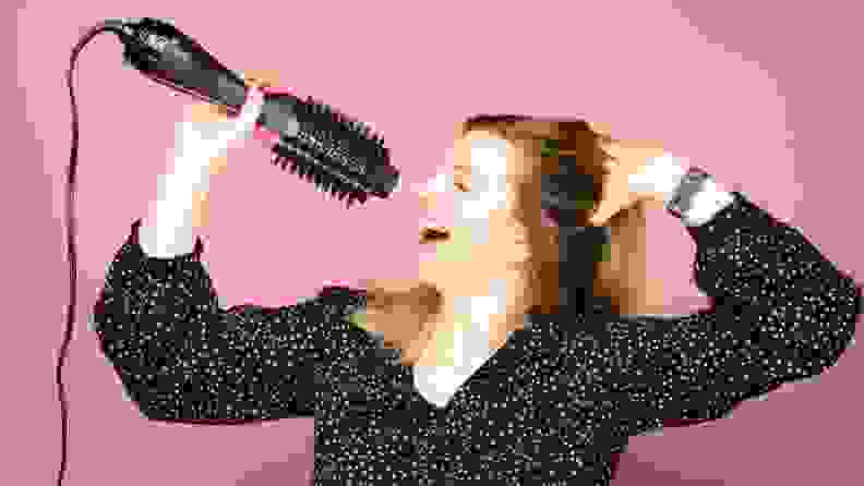A woman "singing" into a Revlon One-Step Hair Dryer Brush as though it were a microphone