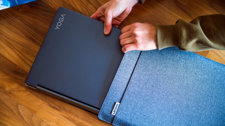 A person putting a laptop into a protective fabric sleeve.