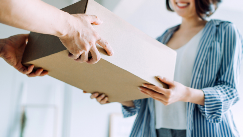 Person using hands to hand off package box to another person.