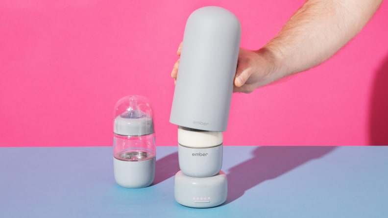 A person grabbing a piece of the Ember Baby Bottle System on a pink and blue background.