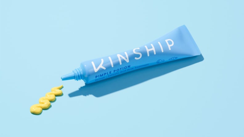 A light blue squeeze tube laying on a light blue background with a yellow squiggle of formula next to it.