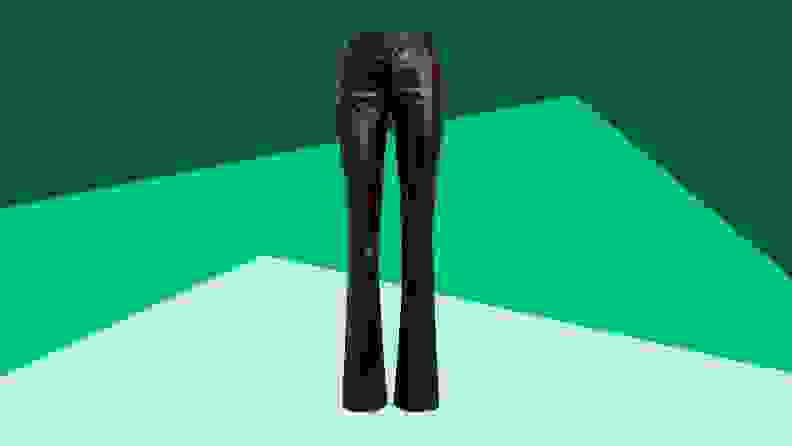 A pair of black leather trousers against a green background.