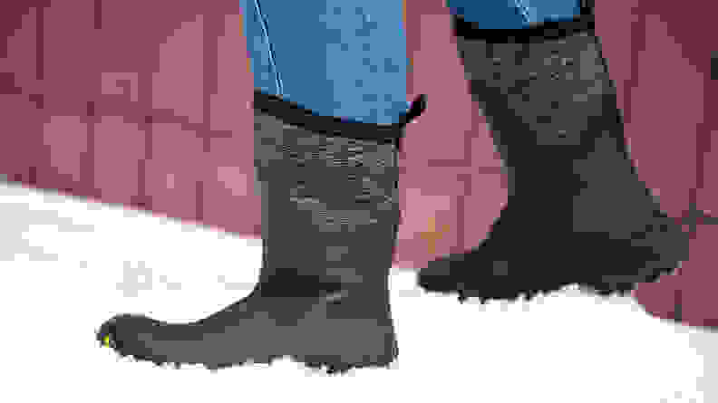 A woman wears a pair of Muck Boots Women’s Arctic Ice Mid-Height winter boots. She is standing in the snow.