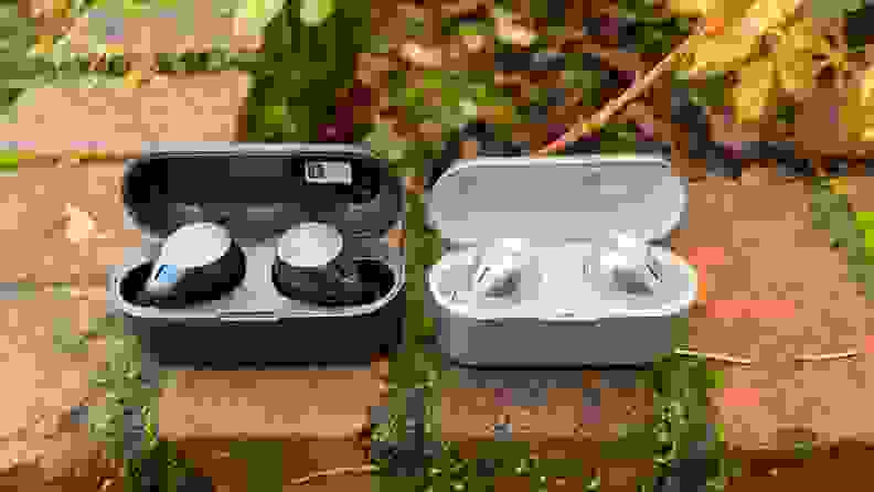 The gunsmoke colored wireless earbuds sit in their charging case with the lid open next to the smaller silver EAH-AZ40 earbuds on a brick ledge.