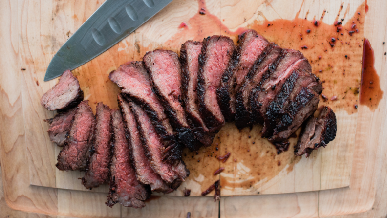 On a cutting board, a long, square-shaped Zabuton wagyu steak is sliced up into thin slices.