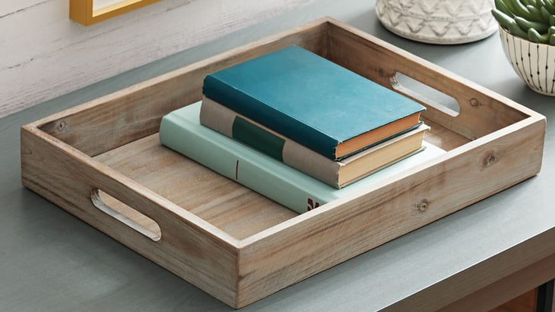 Stack this wooden tray with books and a decorative candle.