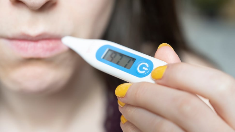 一名妇女用温度计通过口测体温。