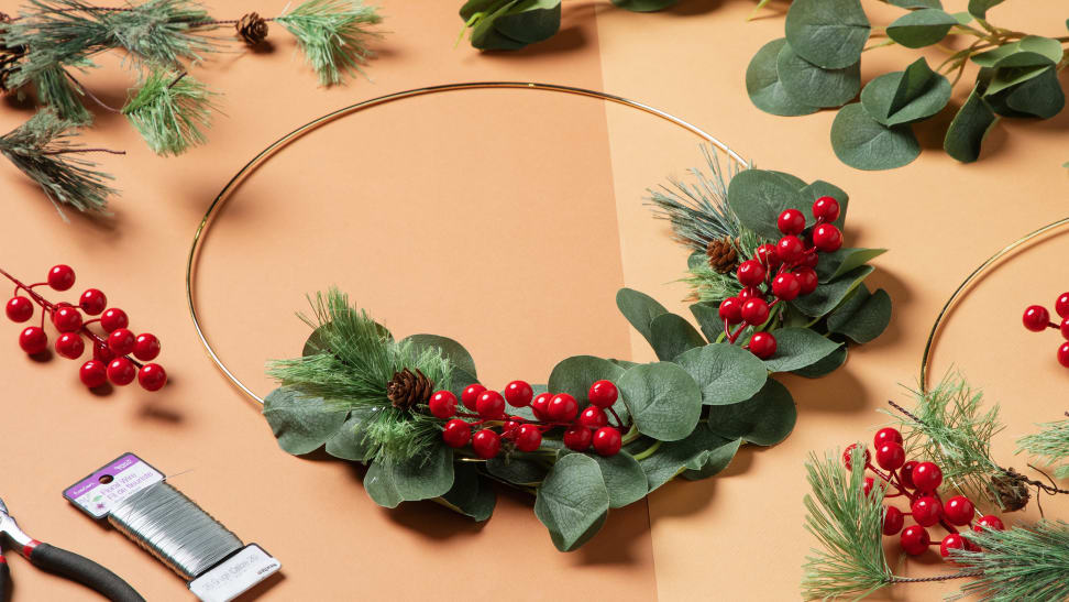 A hoop wreath sitting at the center surrounded by fake flowers and floral wire.