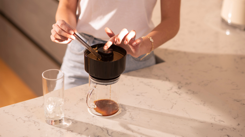 A person is pressing the vacuum button to make coffee using a VacOne coffee maker.