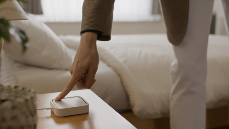 A person reaching down to touch the SmartThings Station.