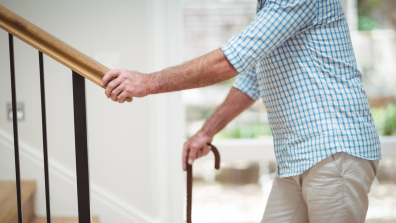 A person using a cane climbs up the stairs