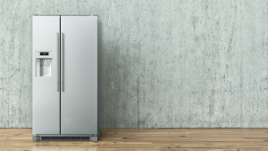 A free-standing refrigerator posed against a blank wall.