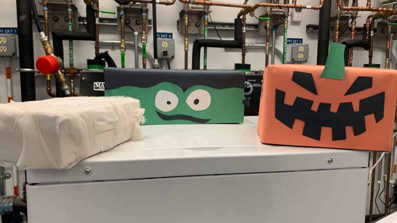 Four boxes adorned with construction paper. From left to right, they look mummified, like a Frankenstein's monster, and like a carved Jack-o'-Lantern.