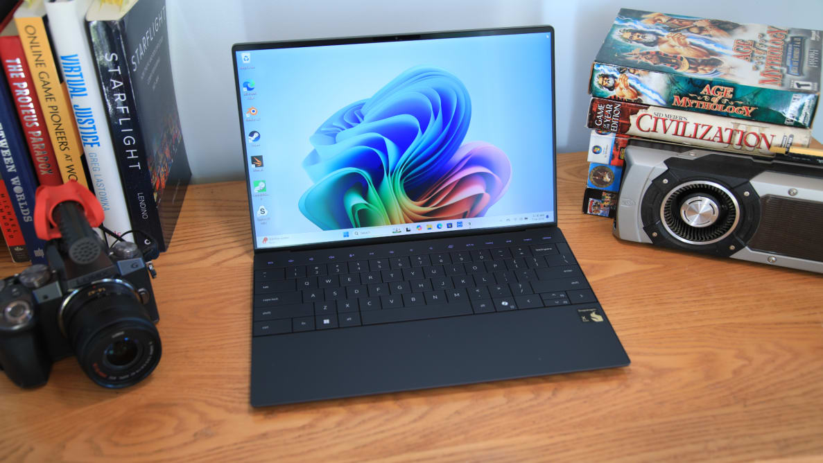 The Dell XPS 13 on a desk surrounded by books and a camera.