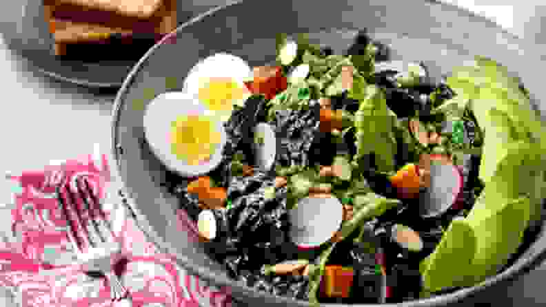 A kale salad with eggs, radish, and dressing.