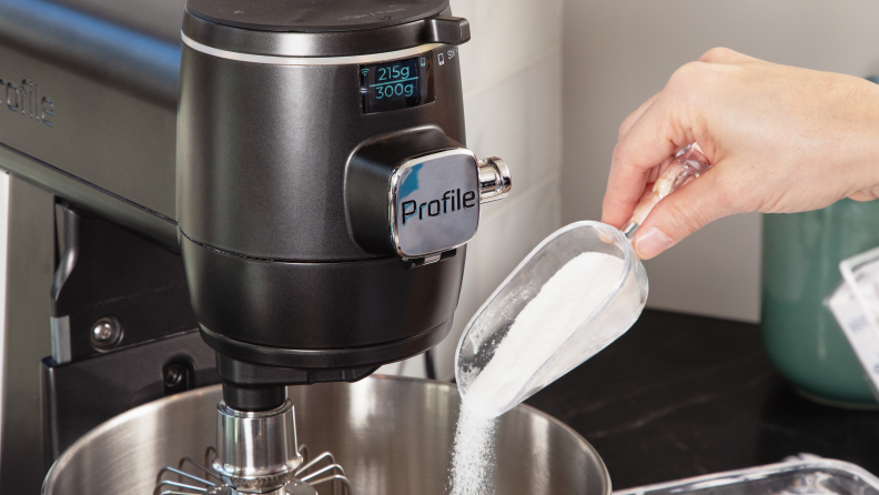A person adds sugar to the smart mixer bowl using the on-board scale.