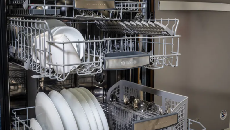 Inside a Bosch dishwasher with white dishes inside the racks.