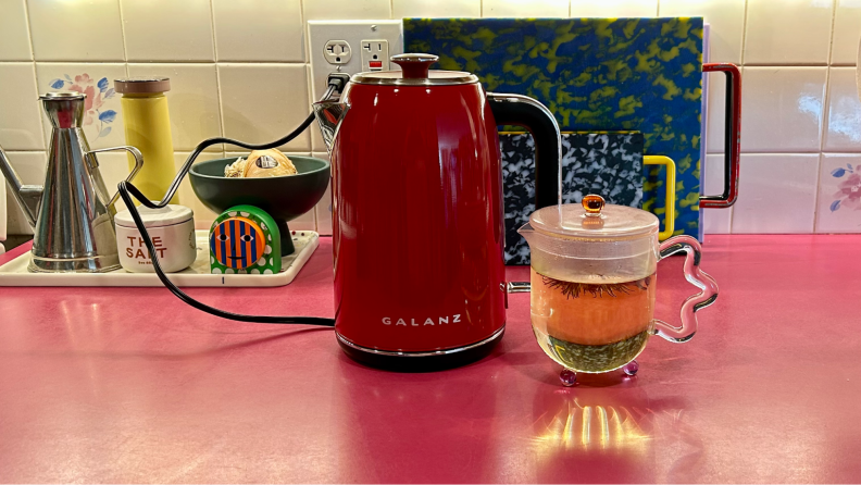 一个格兰仕避署ctric kettle in the color red, next to a small, clear, glass, teapot.