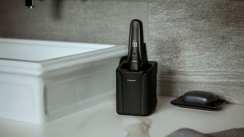 The Panasonic Arc6 electric razor in its charging dock on top of a sink vanity.