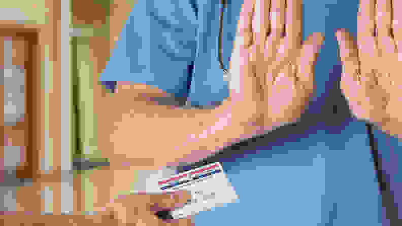 A person raising their hands in rejection of another person offering a card.