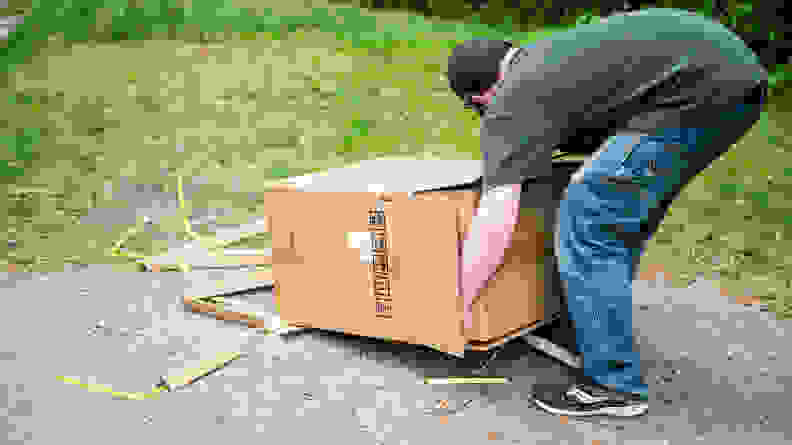 A person lifts a generator out of a cardboard box outside.