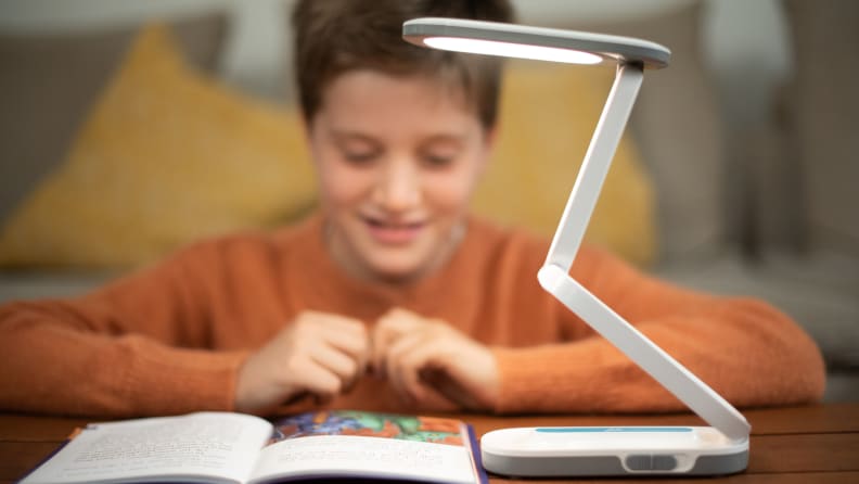 A child reads a book while using the Lili Lamp.