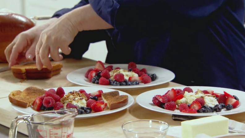 A still from Barefoot Contessa featuring Ina preparing plates of ricotta toast with berries.