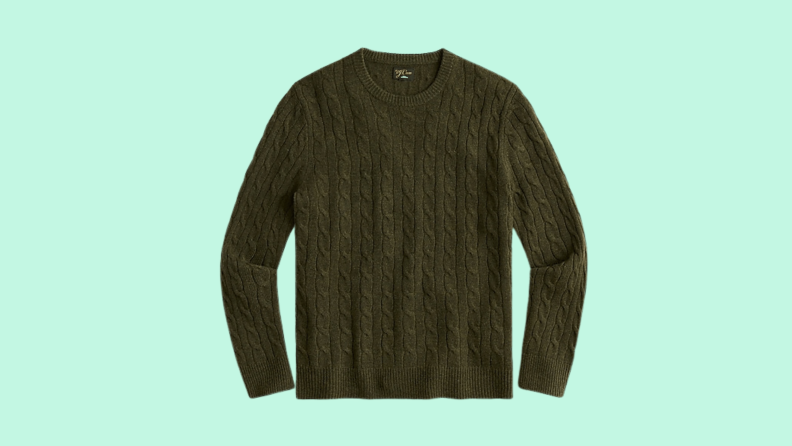 A hunter green cashmere sweater against a light green background.