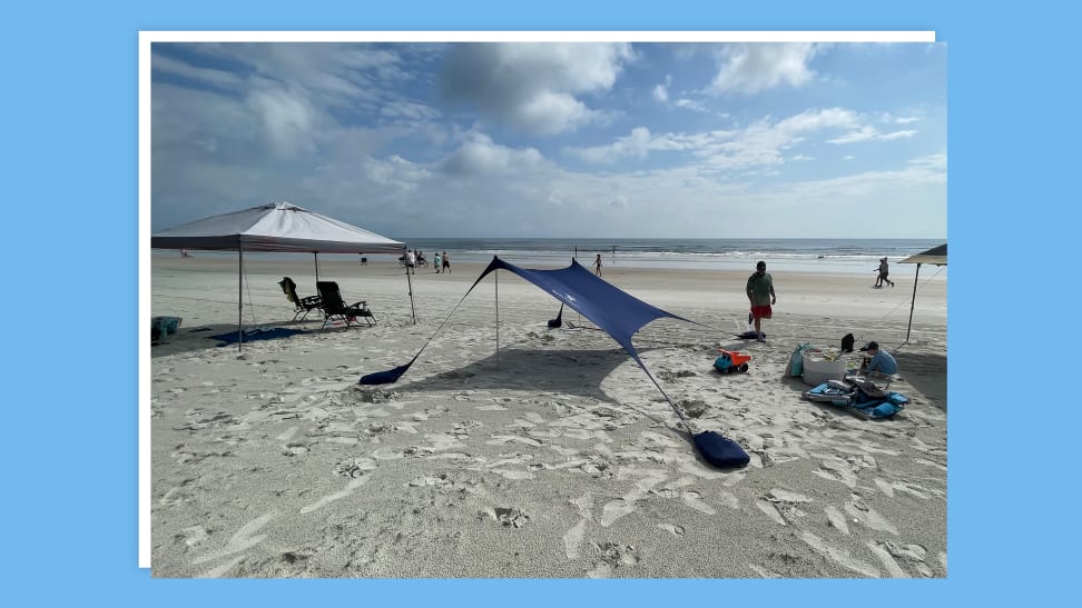 Beach tent propped up in sand outdoors.