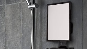 A fogless shower mirror being used for music and for a man to shave.