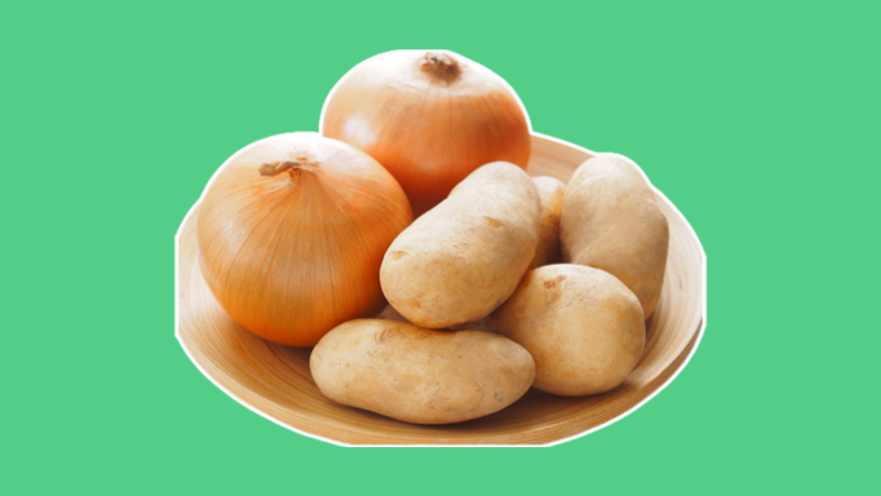 Two brown onions and four potatoes on a plate, against a green background.