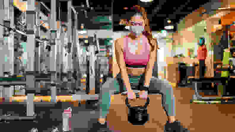 woman squatting with a kettlebell at the gym