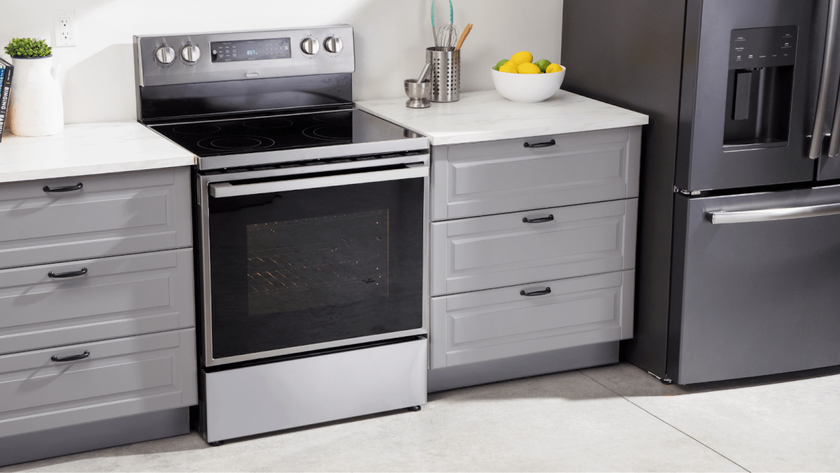 Stainless steel and black Hisense HBE3501CPS 30-in Freestanding Electric Range in between kitchen drawers in modern kitchen indoors.