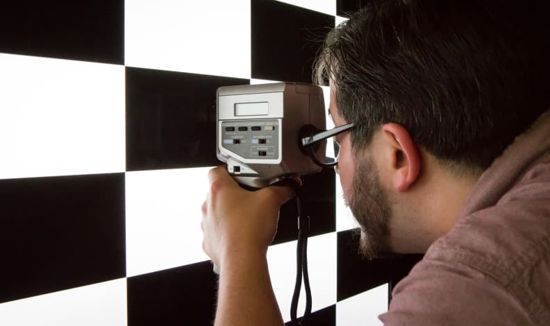 Une Personne Utilise Un Appareil Pour Calibrer La Couleur Et La Luminosité D'Un Écran De Télévision.