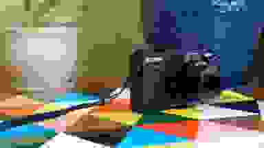 A black Canon point-and-shoot camera rests on a colorful tabletop.
