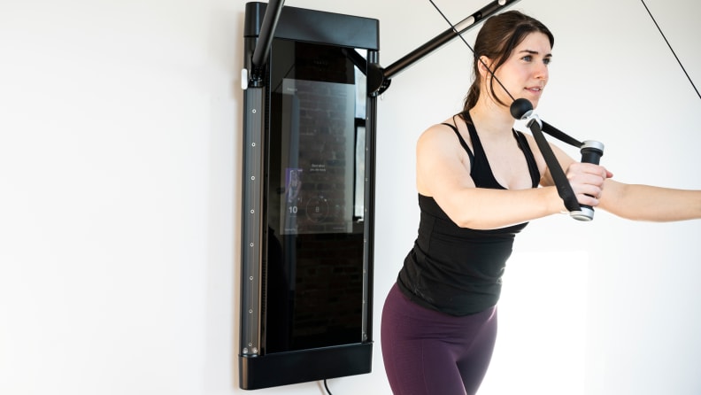 A woman doing chest flys with the Tonal workout mirror.