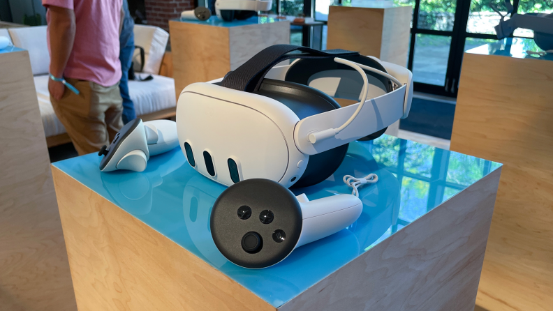A white VR headset with two controllers on either side, the meta quest 3.