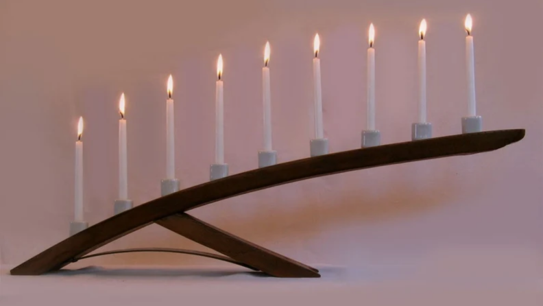 An angled menorah for Hanukkah featuring nine lit candles.