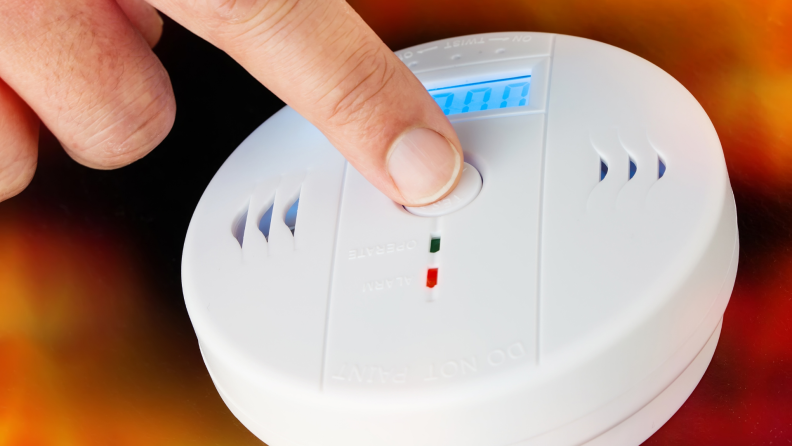 Person pressing the test button on the smoke detector