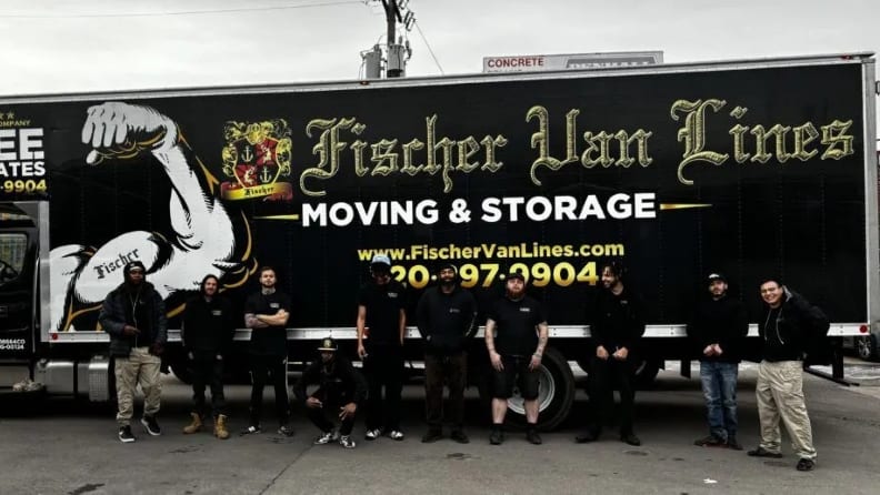 Members of a moving company having their photo taken with their truck behind them