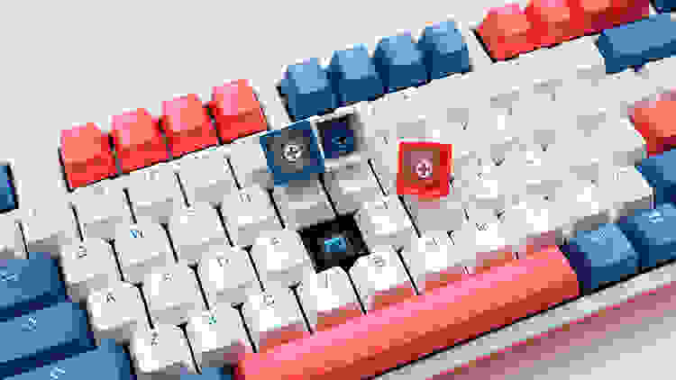 A picture of a keyboard with two keycaps removed, showing the switches beneath.