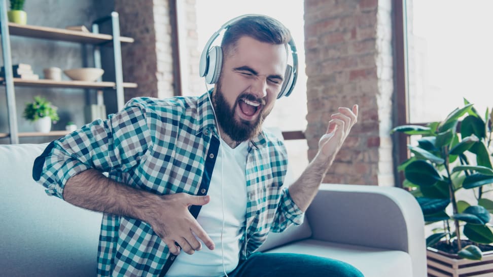 A man listening to headphones while playing the air guitar.
