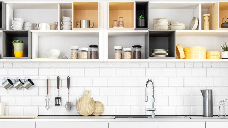 A kitchen with open cabinets full of plates and cups.