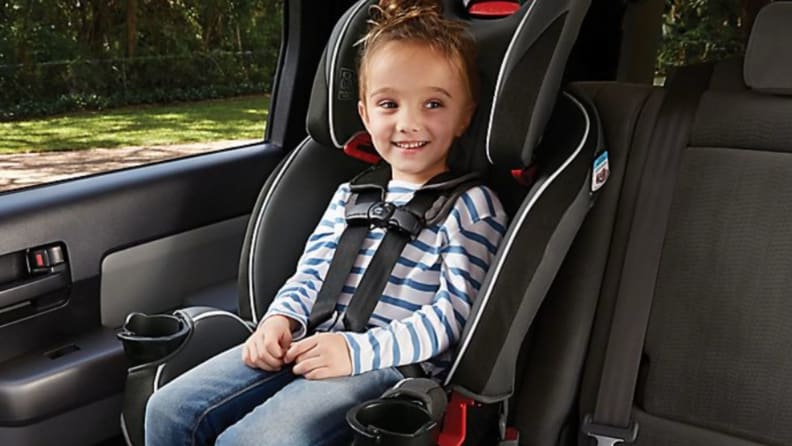 A child sits smiling in his Graco car seat.
