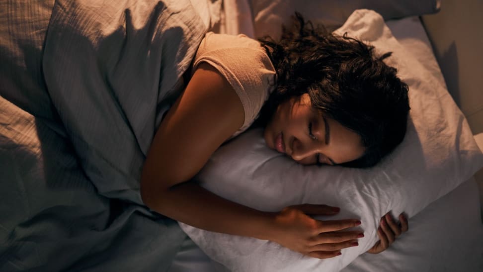 a person curls up with their pillow sleeping on their side