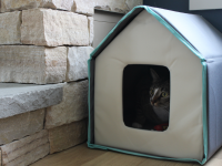 The Frisco Heated Cat House with a cute cat sitting inside.