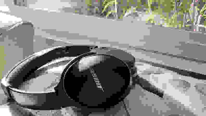 The Bose QC45 headphones sitting atop a pillow in front of a window