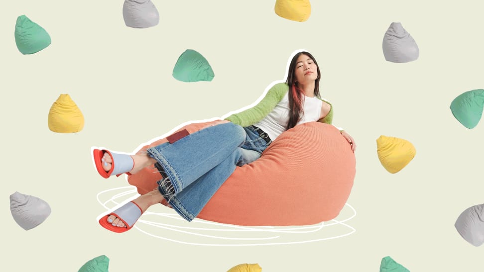 Person lounging sideways on beanbag chair surrounded by assorted colorful beanbags.